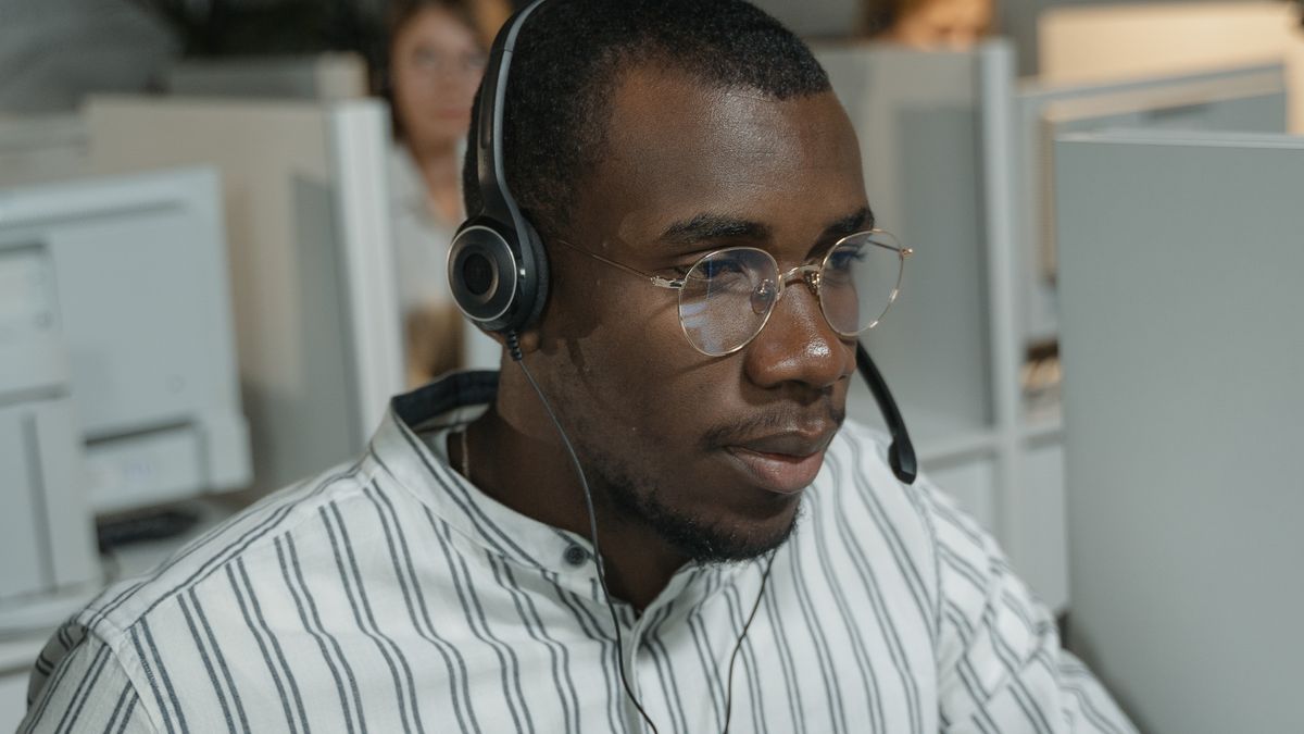 Call centre agent wearing a headset with microphone at their workstation