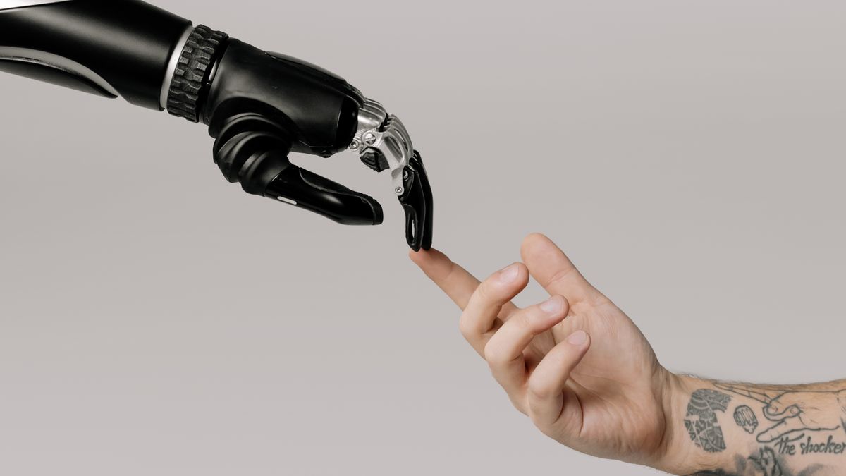 Articulated robotic hand touching a person's index finger with its fingertip against a dark background