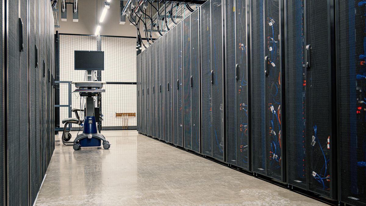 Data centre aisle with server cabinets on both sides and a monitor cart at the far end