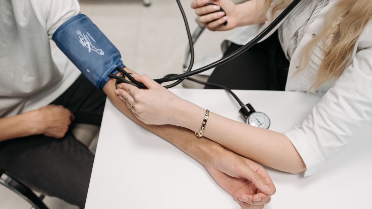 Profesional sanitaria tomando la tensión arterial a una paciente con un tensiómetro de brazo