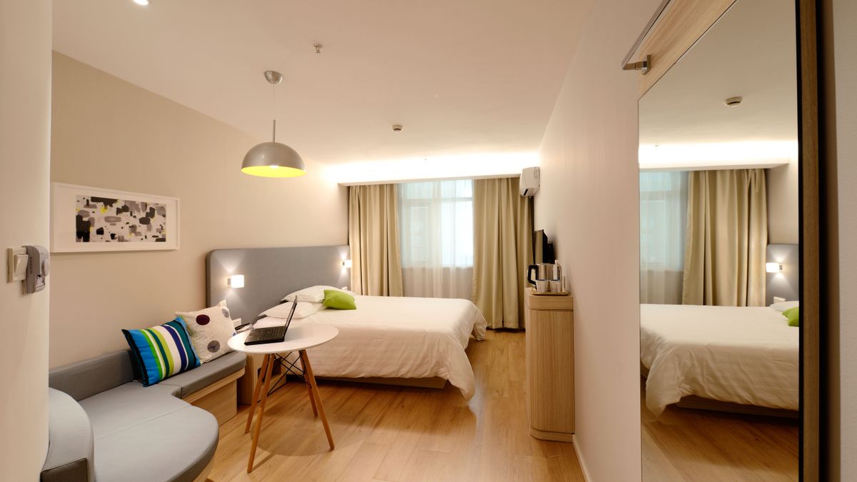 Hotel room with a double bed, a sofa by the window and an open laptop on a small round white table